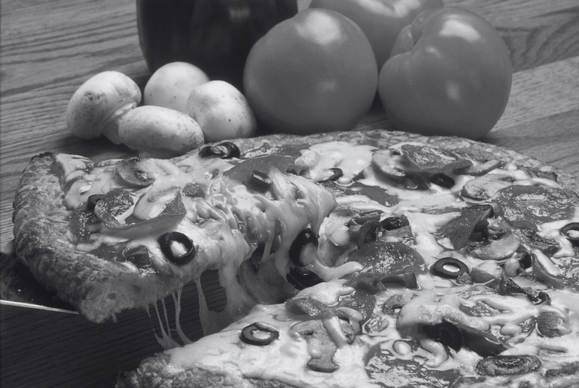 a black and white photo of a pizza on a table